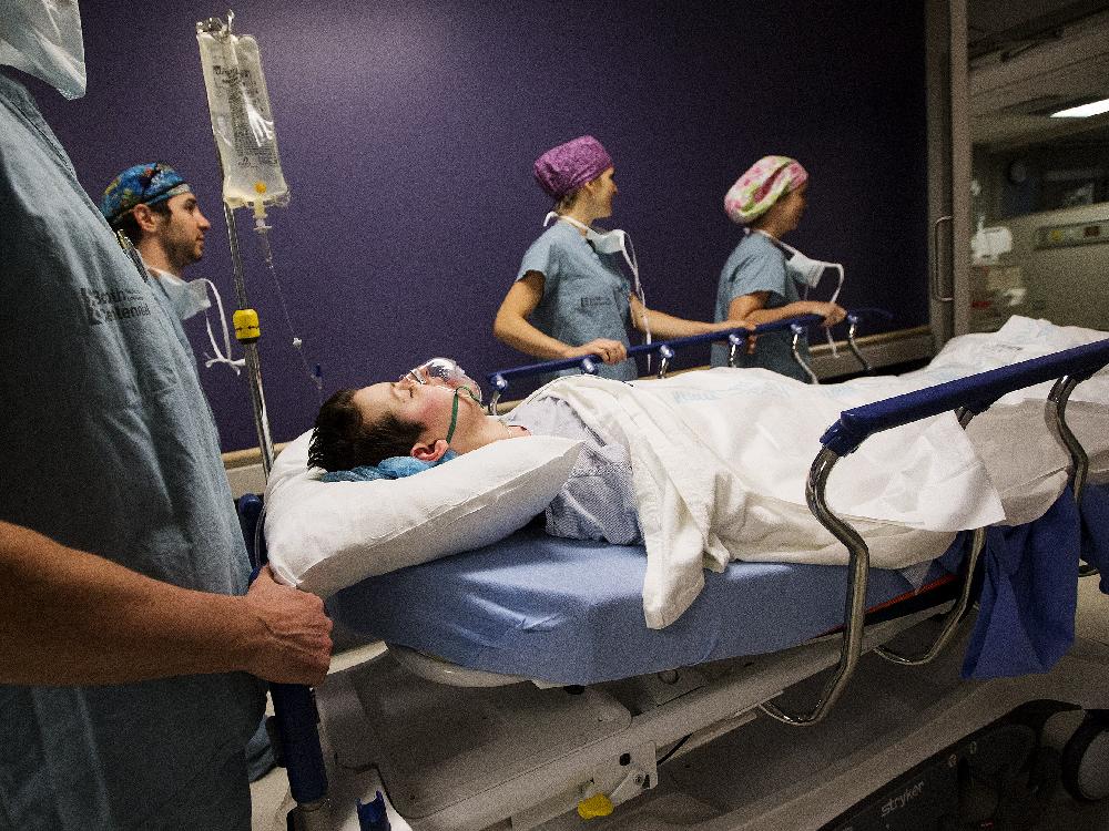 Caroline Noakes who had a double mastectomy is wheeled into the recovery room following her breast implant procedure in the Women's College Hospital in Toronto