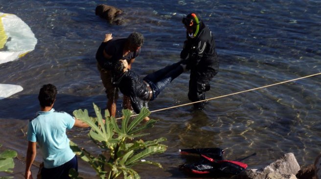 Greek coast guards carry the body of a migrant after a wooden ship carrying migrants sunk near the Greek island