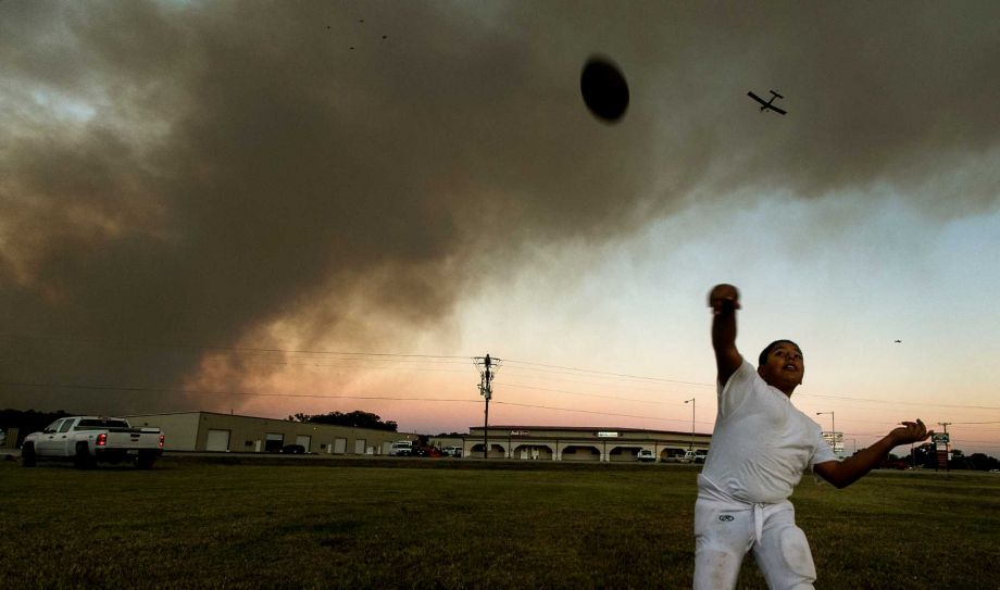 Matthew Maldonado 10 plays catch with his brother Gabriel 12 Tuesday Oct. 13 2015 in Smithville Texas as a single engine air tanker plane begins to make it's drop run overhead towards the Luecke wildfire. (Rodolfo Gonzalez  Austin American-States