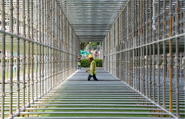 A worker walks under scaffolding for the seating built for the Formula One night race in Singapore