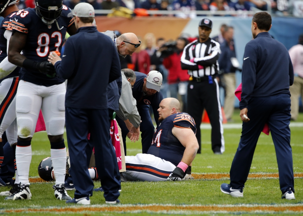 Trainers check on Chicago Bears center Will Montgomery on the field during the first half of an NFL football game against the Oakland Raiders Sunday Oct. 4 2015 in Chicago