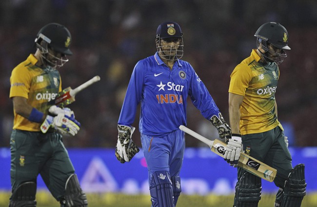 South African batsmen Farhaan Behardien right Jean Paul Duminy, left and Indian captain Mahendra Singh Dhoni center walk back as their second Twenty20 cricket match is disrupted after spectators threw bottles in Cuttack India Monday Oct. 5 2015