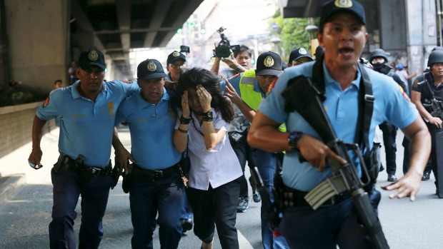 Policemen assist a bus passenger to safety during a robbery incident inside a public bus in Manila on Thursday. Police killed the suspected robber after he took a student hostage