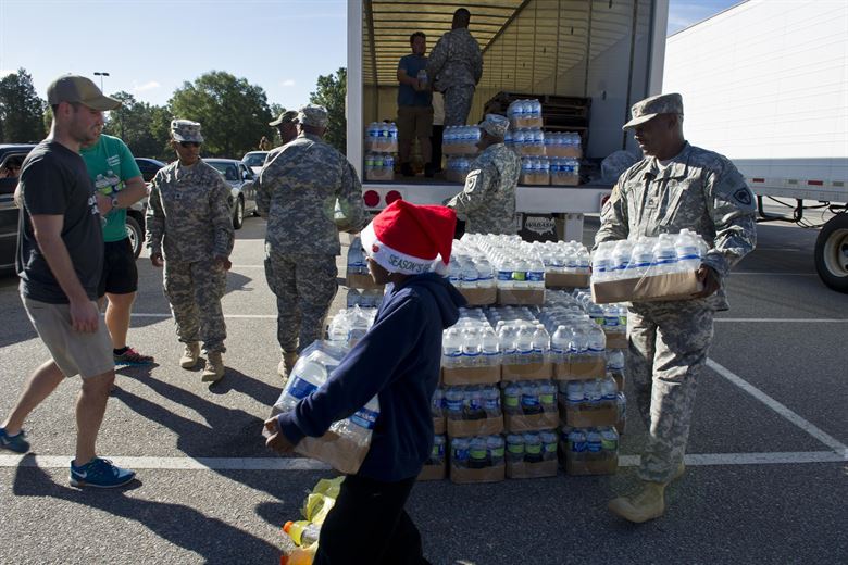 South Carolina Army National Guardsmen from the 742nd Maintenance Company law enforcement personnel and volunteers distribute drinking water to residents affected by flooding caused by Hurricane Joaquin in Columbia S.C. Oct. 6 2015. South Carolina Air