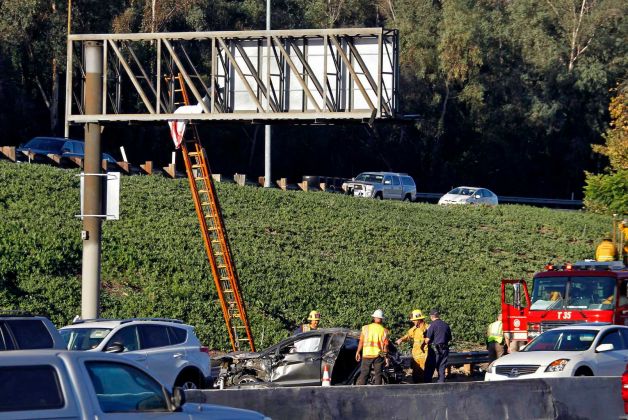 The body of a driver ejected when his car rolled over several times on southbound Interstate 5 is seen where it landed on an overhead freeway sign north of downtown Los Angeles Friday morning Oct. 30 2015. California Highway Patrol officers got a ladder