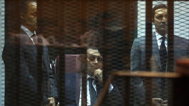 Ousted Egyptian president Hosni Mubarak sits in the defendant’s cage in between his sons Gamal and Alaa as they listen to the verdict in their hearing in a retrial for embezzlement