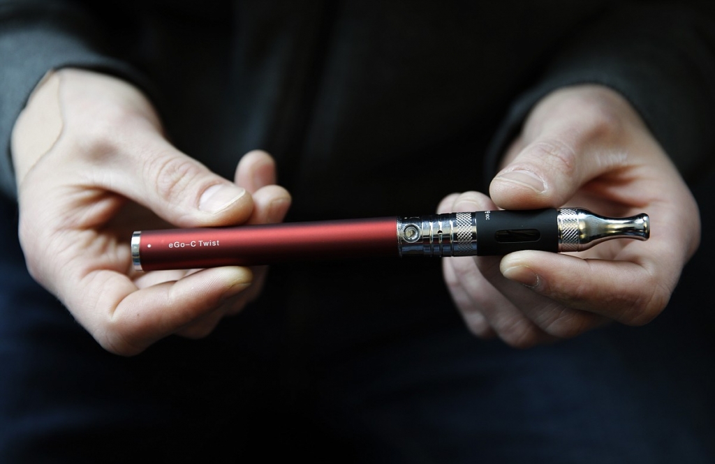 Eric Scheman holds an e-cigarette at Vape store in Chicago. Some schools are taking stricter measures to keep e-cigarettes out of students’ hands even punishing possession of the devices more harshly than regul