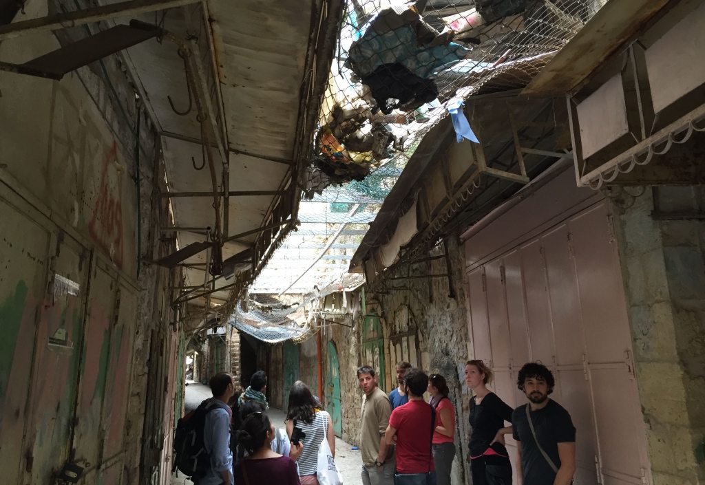 French travelers facilitated by the Catholic Committee Against Hunger and for Development walk the Old City of Hebron where overhead nets catch debris thrown from above