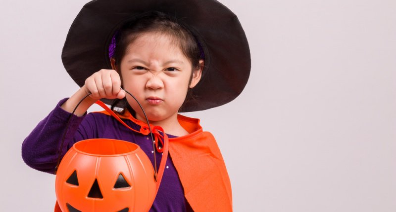 Image Girl in witch costume makes scary Halloween face