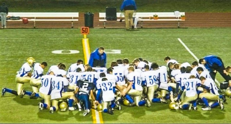 Bremerton High School Coach Joseph Kennedy holds a team prayer