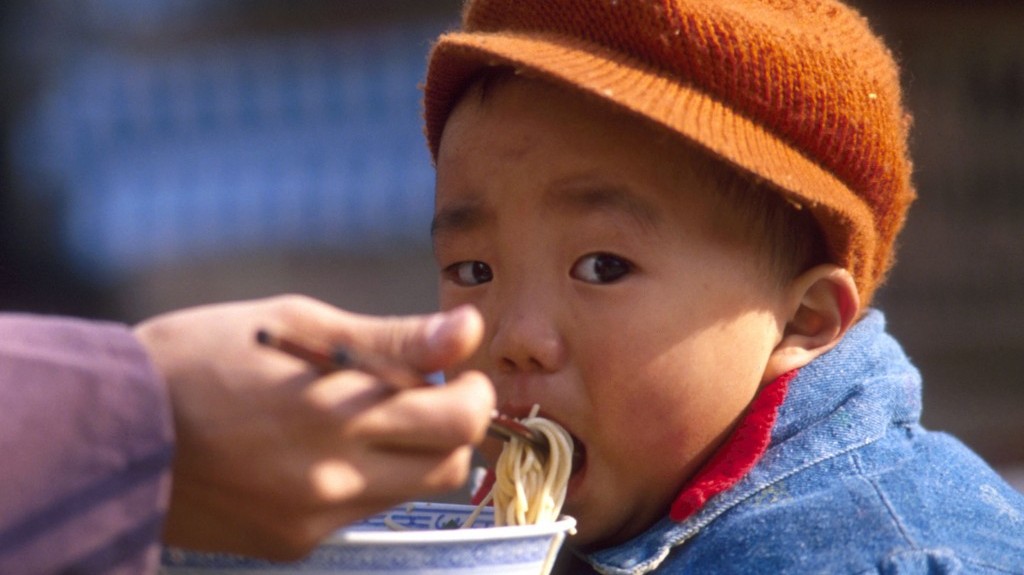 Illustrative A Chinese boy eats noodles in Beijing