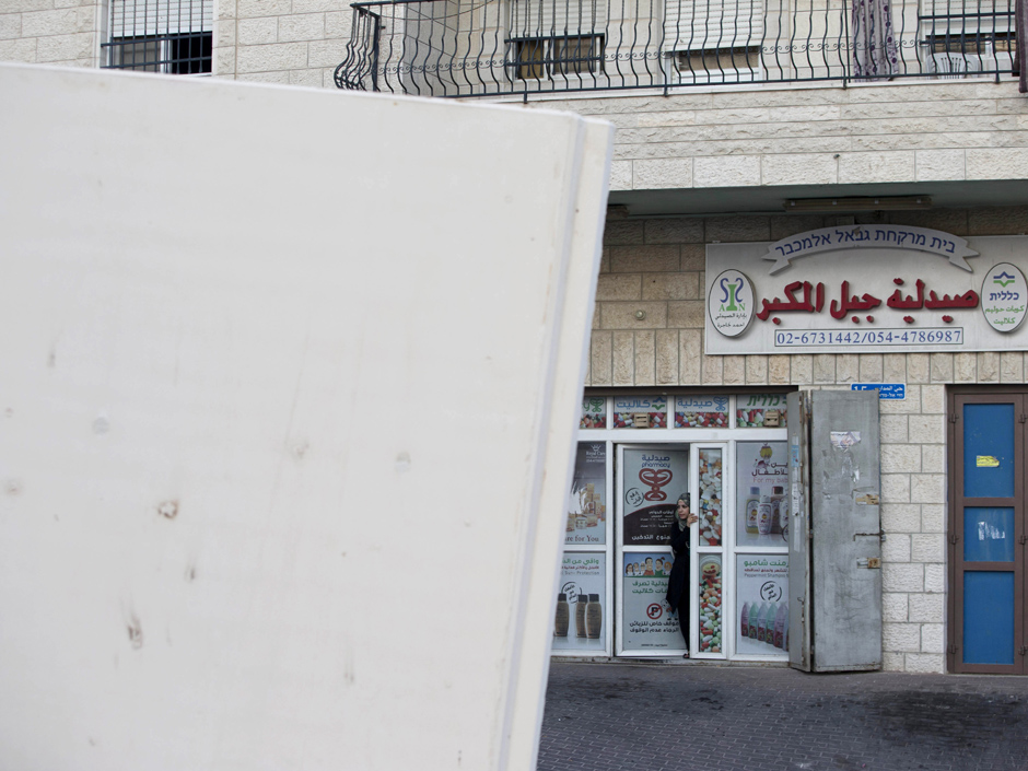 A Palestinian woman looks at concrete barrier between the Arab neighborhood of Jabal Mukaber and the Jewish area of Armon Hanatziv in east Jerusalem Sunday Oct. 18 2015