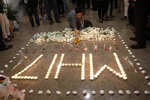 Malaysia Airlines crew member places a flower next to candles forming the letters MH17 after a multi-faith prayers for the victims of the downed Malaysia Airlines Flight 17 at Malaysia Airlines Academy