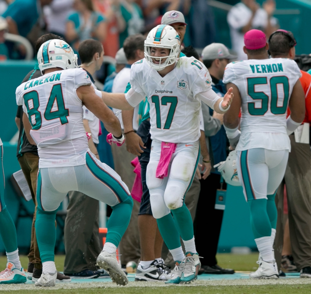 Miami Dolphins quarterback Ryan Tannehill celebrates a touchdown pass completed to Miami Dolphins running back Lamar Miller with Miami Dolphins tight end Jordan Cameron at Sun Life Stadium in Miami Gardens Florida