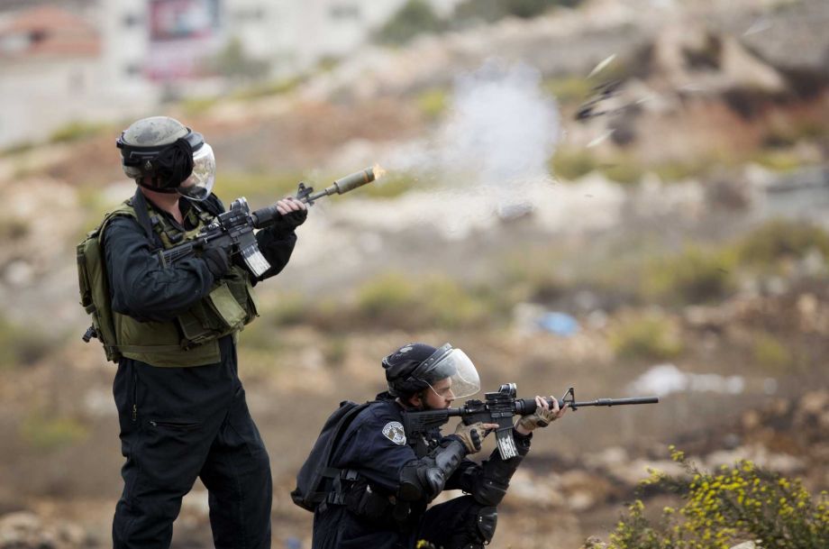 An Israeli border policeman fires rubber coated bullets during clashes with Palestinian protesters during clashes near Ramallah West Bank Friday Oct. 23 2015. Elsewhere Muslim prayers at Jerusalem's holiest site which has been the epicenter of weeks