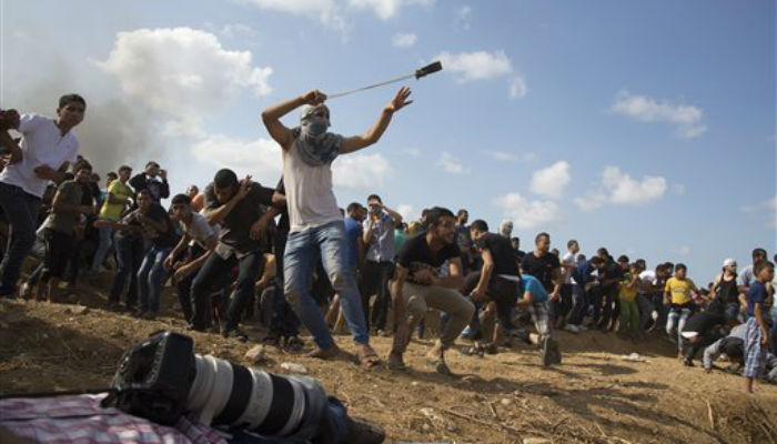 A Palestinian protester hurls stones at Israeli soldiers during clashes on the Israeli border Eastern Gaza City Friday Oct. 9 2015. At least four attacks — three by Palestinians and one by an Israeli — as well as deadly clashes along the Gaza borde