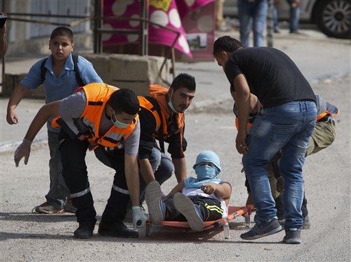 Palestinians carry an injured man during clashes with Israeli troops at Qalandia checkpoint between Jerusalem and the West Bank city of Ramallah Tuesday Oct. 6 2015. A new generation of angry disillusioned Palestinians is driving the current wave of