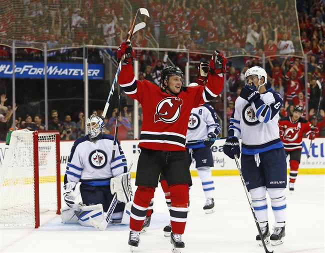 New Jersey Devils forward Jiri Tlusty front left of the Czech Republic celebrates his goal past Winnipeg Jets goalie Michael Hutchinson as center Alex Burmistrov, of Russia looks back during the second period of an NHL hockey game in Newark N.J