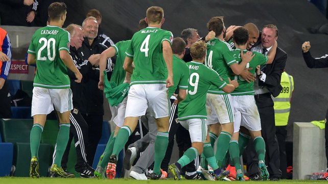 Josh Magennis and team mates mob Michael O'Neill after their second goal