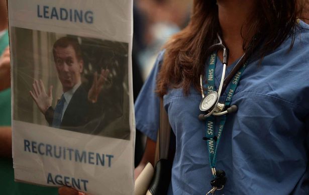 A woman holds a placard during the 'Let's Save the NHS&#x27 rally and protest march by junior doctors in London