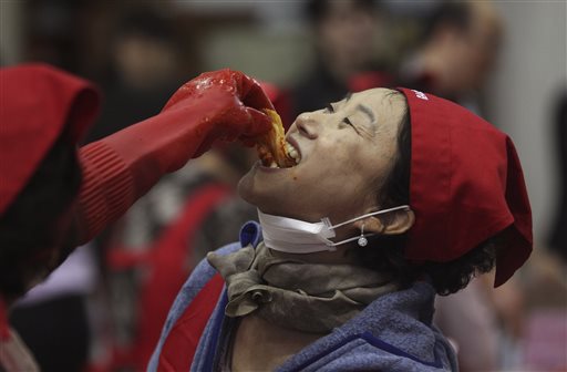 An unidentified woman tastes kimchi traditional pungent vegetable as they make kimchi to donate to needy neighbors for winter preparation at a government building in Seoul South Korea Wednesday Oct. 28 2015. About 100 volunteers made 5,500kg of kimc