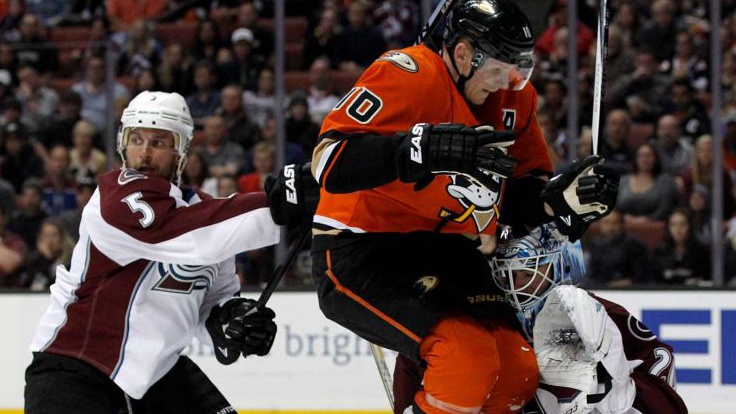 Anaheim Ducks right wing Corey Perry leaps against Colorado Avalanche goalie Reto Berra, of Switzerland with defenseman Nate Guenin nearby