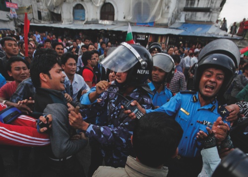 Nepalese protesters try to clash with policemen after burning a copy of the new constitution during the protest organized by splinter of the Maoist party