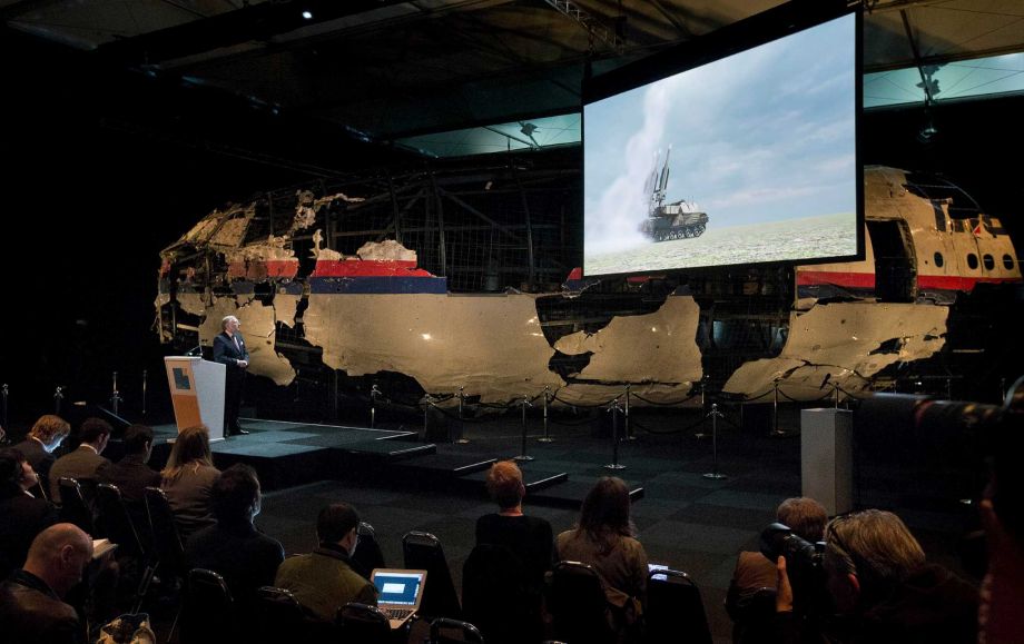 A video show the launch of a BUK missile while a part of the reconstructed forward section of the fuselage is displayed behind as Tjibbe Joustra left head of the Dutch Safety Board presents the board’s final report into what caused Malaysia Airlines