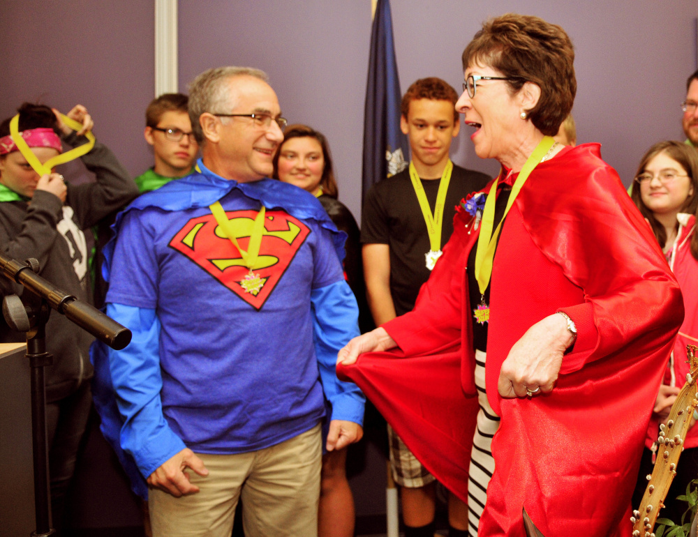 Boys and Girls Club of Greater Augusta board member Dr. Roy Miller left watches as U.S. Sen. Susan Collins models the cape with a lightning bolt and letter C that he presented her Saturday during an awards ceremony at Kaplan Un