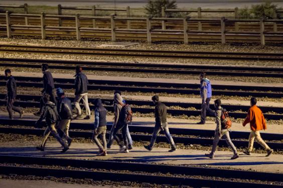 Migrants walk along railway tracks at the French Eurotunnel terminal in July