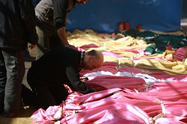 Syrian relatives mourn as corpses are piled up after a reported airstrike by Syrian government forces on the rebel-held town of Douma