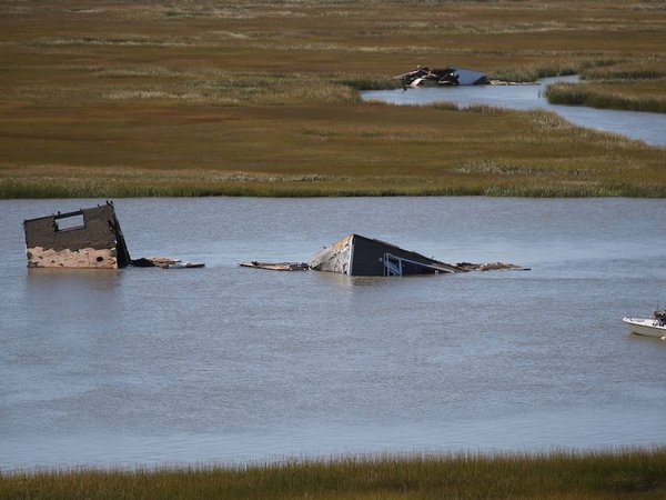 A fishing boat passes by a house that floated away in Grassy Sound during the weekend storm remains stuck in a tidal creek Tuesday Oct. 6 2015 in Middle Township N.J. MANDATORY CREDIT