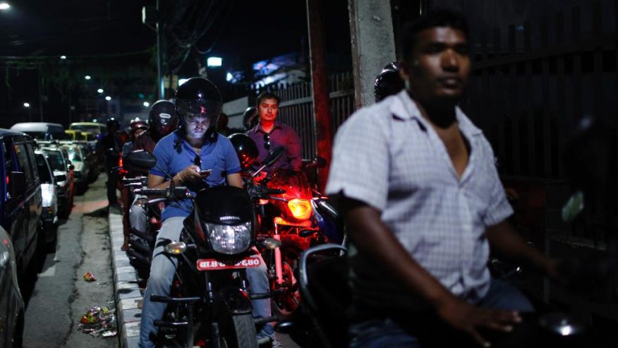 Nepalese motorists wait for their turn to fill fuel on their motorbikes at a fuel pump run by the Nepalese police in Kathmand