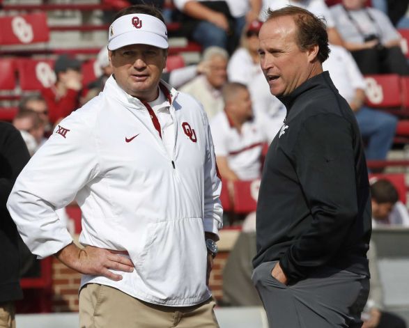 Oklahoma head coach Bob Stoops left talks with West Virginia head coach Dana Holgorsen right before an NCAA college football game in Norman Okla. Saturday Oct. 3 2015