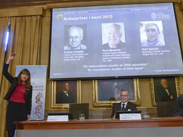 Professor Sara Snogerup Linse left explains why the laureates were awarded as Goran K. Hansson centre and Claes Gustafsson members of the Nobel Assembly sit during a press conference at the Royal Swedish Academy in Stockholm Wednesday Oct. 7 2015