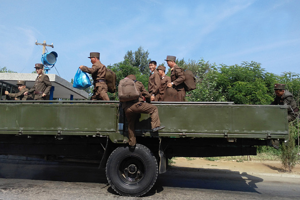 Korean People's Army soldiers climb up a truck