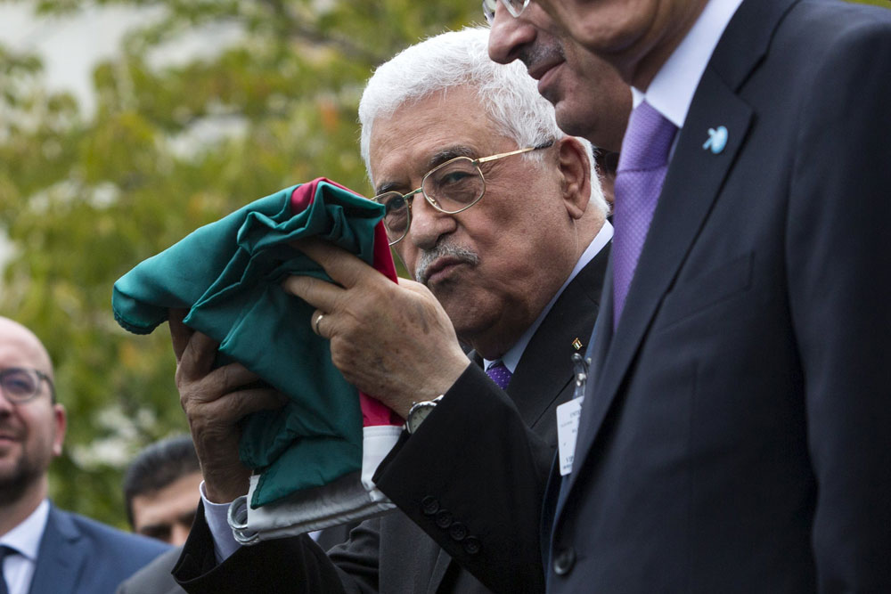 Palestinian President Mahmoud Abbas holds a Palestinian flag