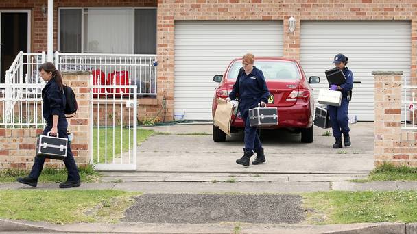 Officers leave a home in the Sydney suburb of Guildford during a series of raids in connection with the murder of a civilian police worker