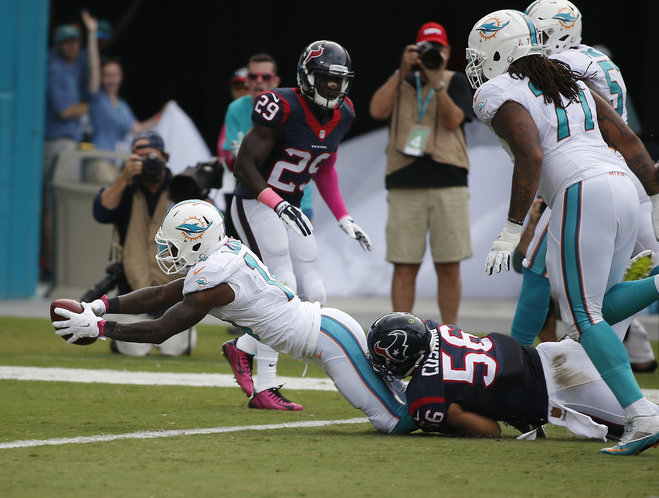 Miami Dolphins wide receiver Jarvis Landry scores a touchdown as he is tackled by Houston Texans inside linebacker Brian Cushing during the first half of an NFL football game Sunday Oct. 25 2015 in Miami Gardens Fla