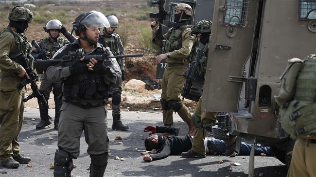 Israeli soldiers and border guards stand next to a wounded Palestinian who was shot by Israeli forces during clashes close to the illegal Beit El settlement on the outskirts of the occupied West Bank city of Ramallah