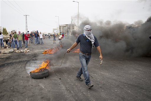 Palestinians burn tires during clashes with Israeli troops near Ramallah West Bank Friday Oct. 23 2015. Elsewhere Muslim prayers at Jerusalem's holiest site which has been the epicenter of weeks of unrest ended peacefully on Friday as the firs