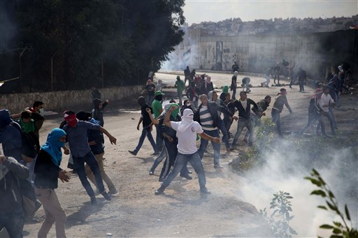 Palestinian students hurl stones at Israeli troops over the separation barrier during clashes following a protest near the Al Quds University in the West Bank village of Abu Dis near Jerusalem Wednesday Oct. 28 2015