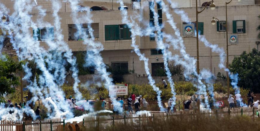 Palestinians run from tear gas fired by Israeli troops near Ramallah West Bank Saturday