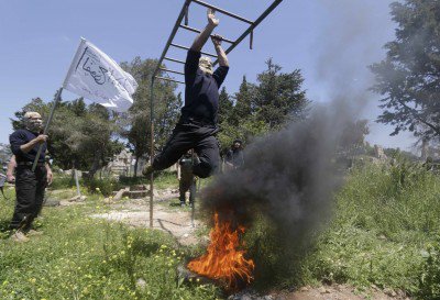 Rebel fighters from 'the First Regiment&#039, part of the Free Syrian Army swing from bars as they participate in a military training in the western countryside of Aleppo