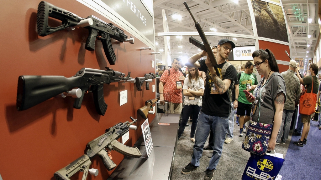 People examine rifles on display at the annual National Rifle Association convention in Nashville Tenn. in April