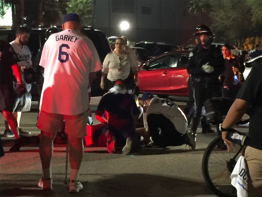 People tend to an injured person following a fight in the Dodger Stadium parking lot on Oct. 9 2015