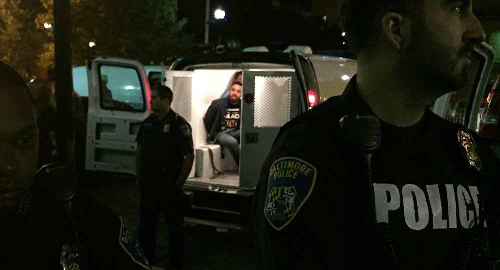 Police stand near vans holding protesters early Thursday Oct. 15 2015 in Baltimore