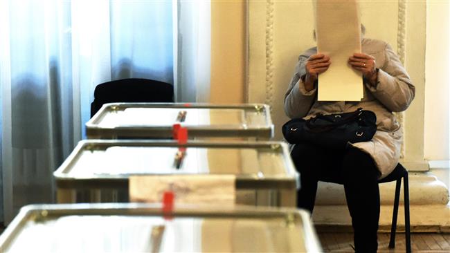 A woman examines her voting ballot at a polling station in Kiev Ukraine