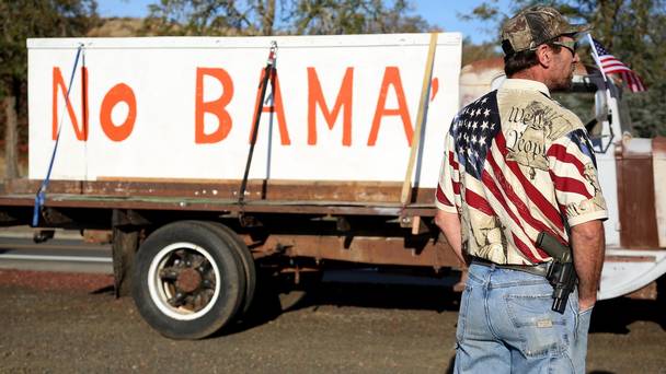 Gun-toting protester Michael Johnson waits outside Roseburg Municipal Airport for Barack Obama's arrival to meet families of the college shooting victims