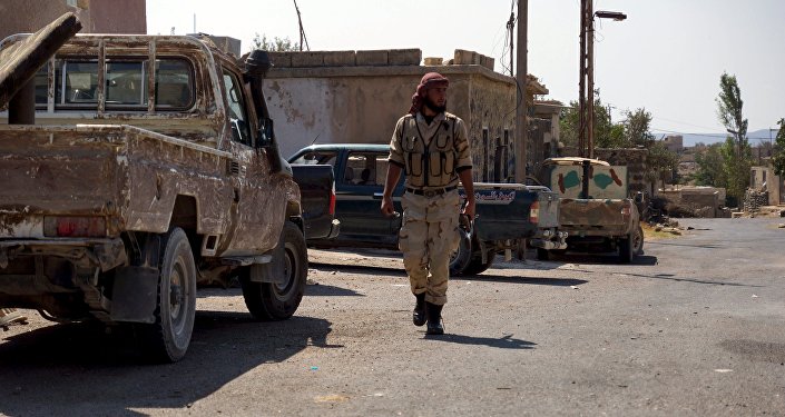 A Free Syrian Army fighter walks near military vehicles during what they said was preparations for an operation to strike at forces loyal to Syria's president Bashar Al Assad in order to break a siege on the city of Beit Gin located in western countryside